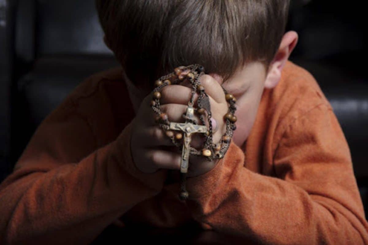 Niño rezando el Santo Rosario