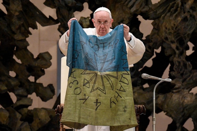 ¡Fin a la guerra! pide el Papa con una bandera de ciudad masacrada