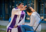 Sacerdote absolviendo a una joven luego de confesarse ante el intermediario de Dios.