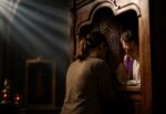 Mujer confesándose con un sacerdote en un confesionario de iglesia durante el Sacramento de la Penitencia y la Reconciliación para recibir la absolución de sus pecados.
