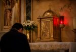 Lámpara roja encendida junto al Sagrario en una iglesia católica, signo de la presencia real de Jesucristo en la Eucaristía.